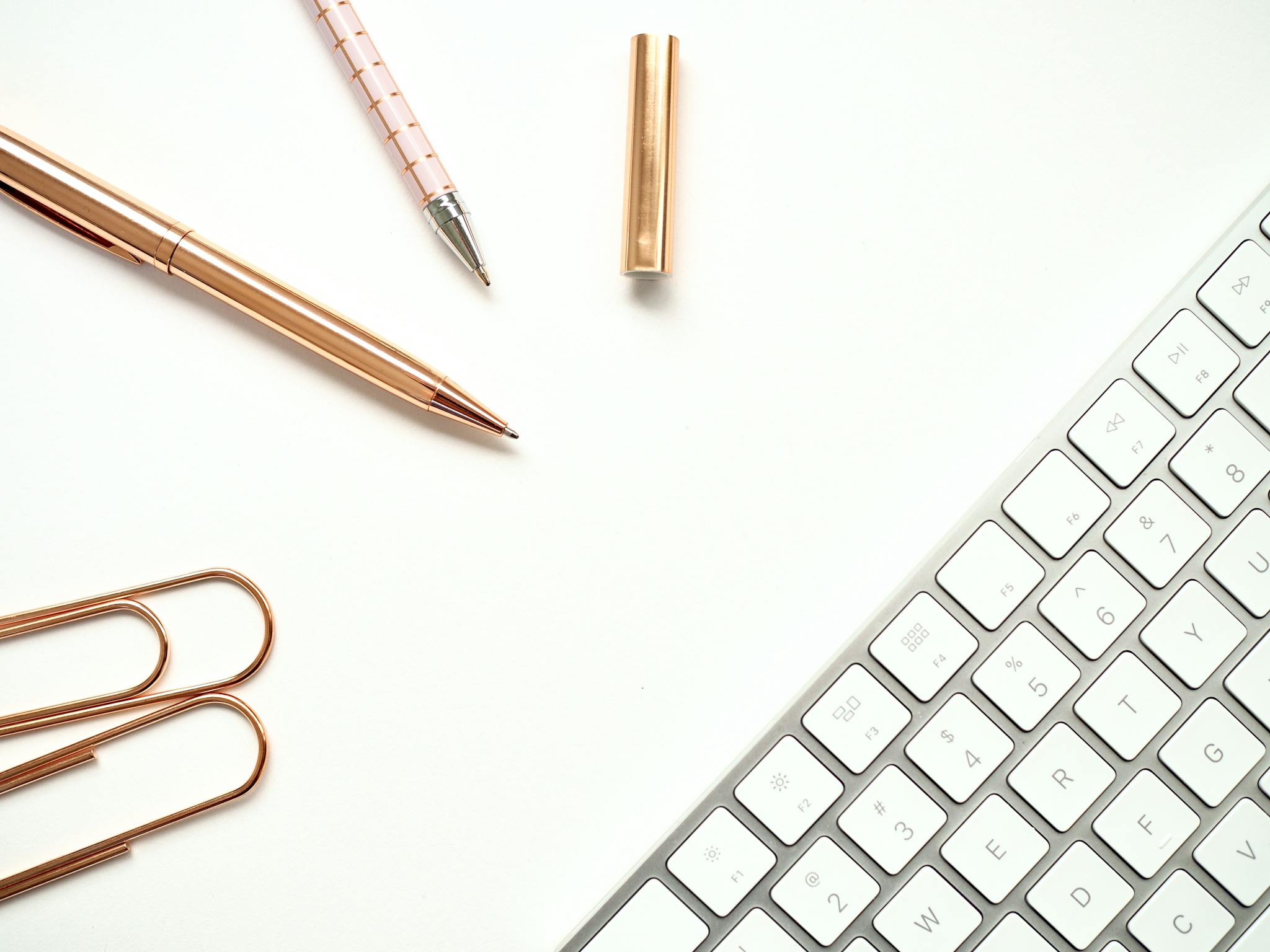 Pens Near Keyboard and Paper Clips